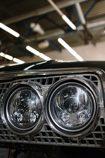 Detailed view of classic car headlights in a workshop setting.
