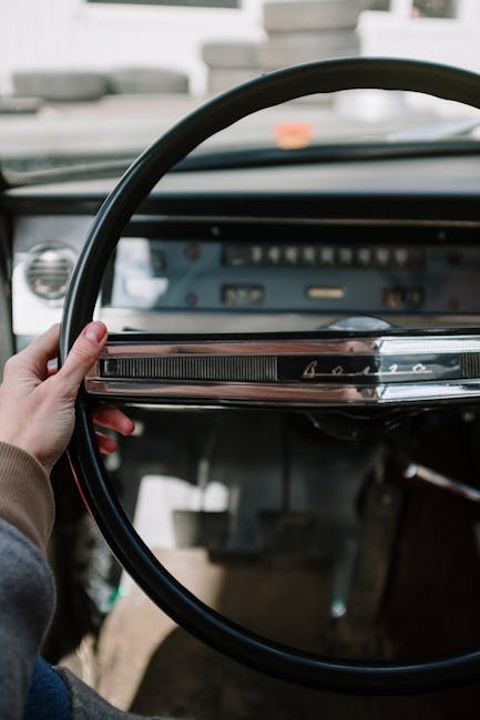 Close-up of a vintage car interior featuring a classic steering wheel with retro design elements.